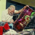 Ed Big Daddy Roth pinstriping a trash can at moon Eyes Christmas party
